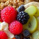 Primo piano di mani che preparano una bowl di cereali e frutta fresca
